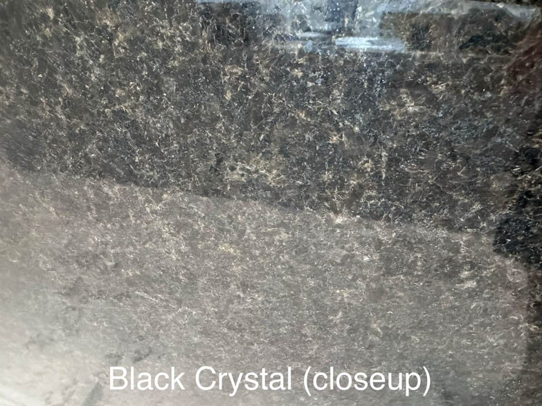 Closeup of a polished black crystal surface with a speckled pattern of light and dark mineral flecks. The words Black Crystal (closeup) appear at the bottom of the image.