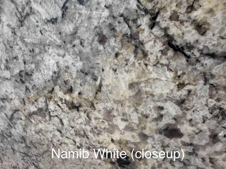 Close-up of Namib White granite, showing a textured pattern of white, gray, and black minerals. The surface has a mottled, speckled appearance. Text at the bottom reads Namib White (closeup).