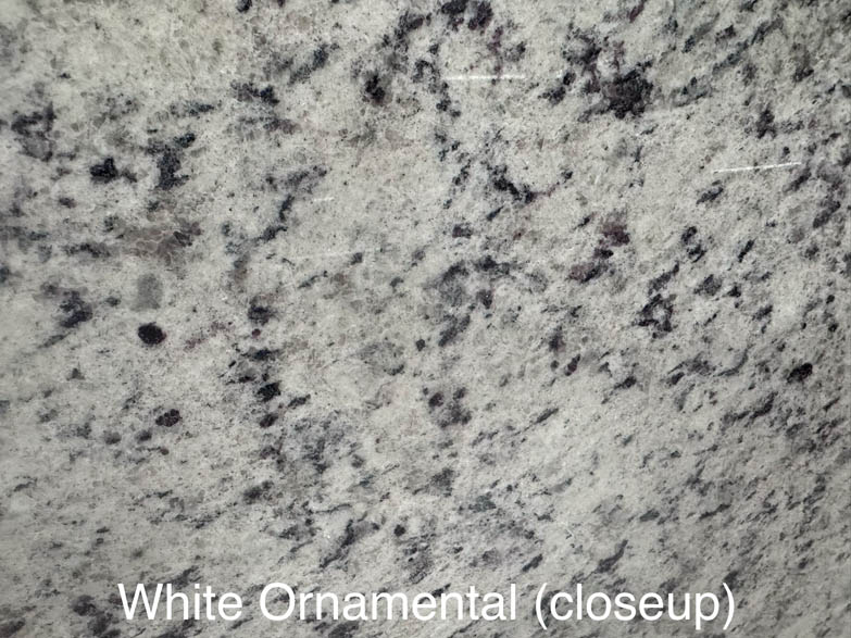 Close-up of White Ornamental granite, showing a light gray background with scattered dark gray and black mineral specks. The image has the label White Ornamental (closeup) at the bottom.